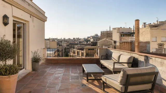 Terrasse d’un penthouse à Barcelone au-dessus des toits de l’Eixample dans une lumière chaude de fin d’après-midi