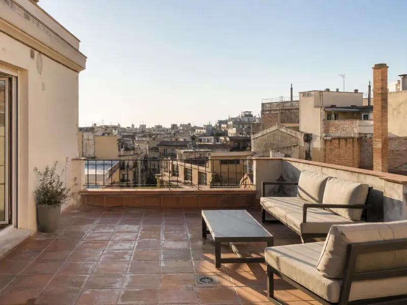 Terraza de un ático de Barcelona sobre los tejados del Eixample con luz cálida de última hora de la tarde