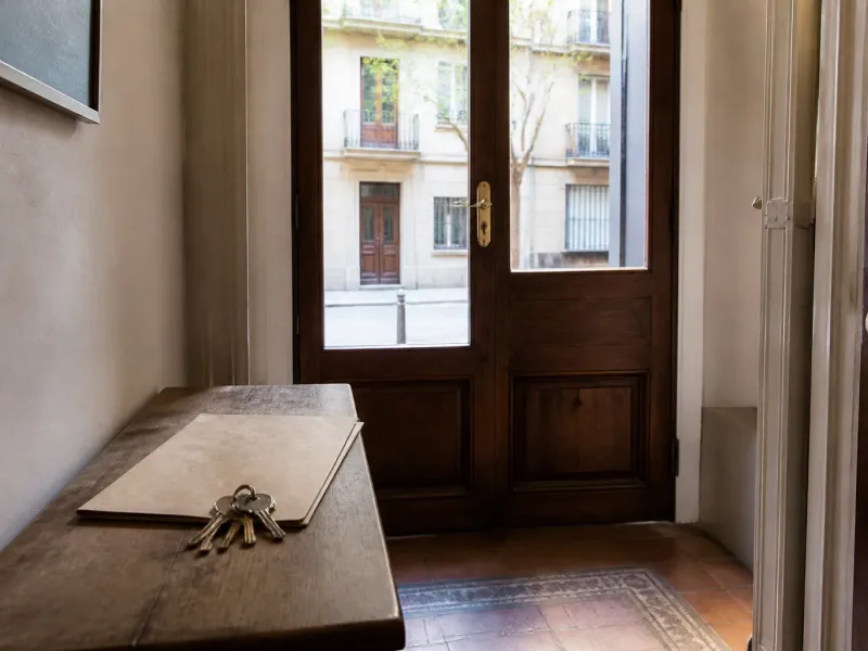 Llaves y una carpeta de contrato sobre una consola de madera en el umbral de un piso de Barcelona