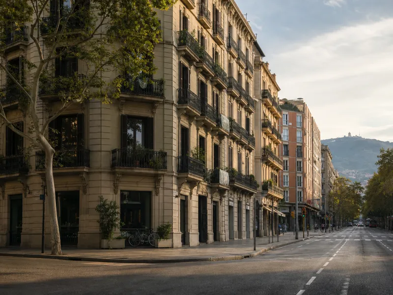 Eixample street with historic balconies, newer apartments and Montjuïc in the distance